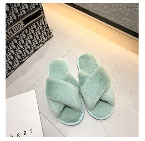 Gros plan de chaussons croisés en peluche vert clair sur un sol en marbre chic.