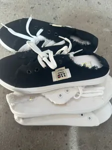 Primer plano de zapatos de lona deshilachados en blanco y negro sobre cemento