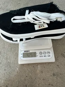 Vista detallada de un zapato mule de lona negra pesado en una báscula digital blanca