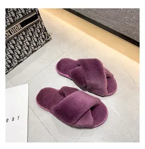 Gros plan de chaussons en peluche violette à brides croisées sur un sol en pierre