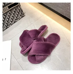 Vue détaillée de chaussons en peluche violets à brides croisées sur le marbre