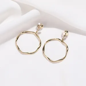 Détail de boucles d'oreilles créoles dorées torsadées avec clips pour oreilles non percées