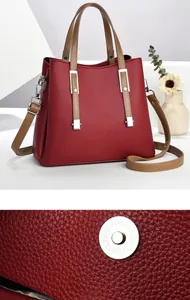 Nahaufnahme der Lederstruktur und des Magnetverschlusses einer weinroten Handtasche