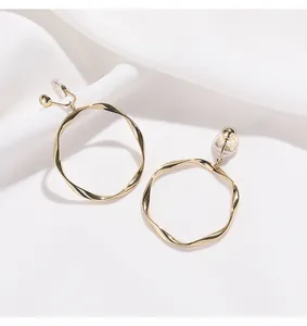Détail rapproché d'élégantes boucles d'oreilles clips créoles dorées torsadées