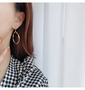 Vue détaillée de boucles d'oreilles créoles dorées torsadées sur un mannequin