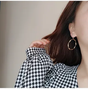 Gros plan de boucles d'oreilles clips créoles dorées torsadées sur une femme asiatique
