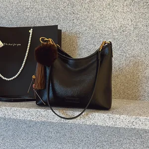 Stylish black soft leather hobo bag for women with tassel and pom-pom charm accessory