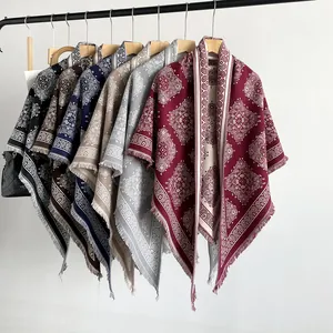 Collection of various vintage paisley pattern triangle shawls on a clothing rack