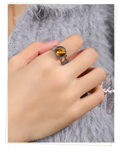 Close-up detail of a women's titanium steel ring featuring a round natural tiger's eye stone