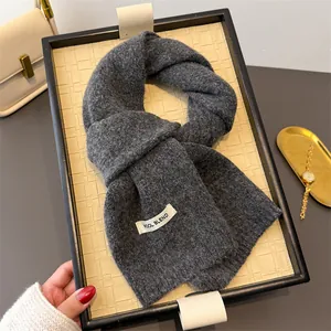 Nahaufnahme eines dunkelgrauen Strickschals aus Wollmischung auf einem Dekotablett.