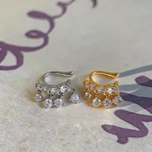Κοντινό πλάνο με ασημένια και χρυσά ear cuffs με λαμπερές κρεμαστές πέτρες ζιργκόν