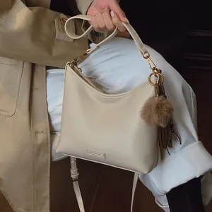 Elegant beige soft leather commuter handbag for women with fur pom-pom and tassel