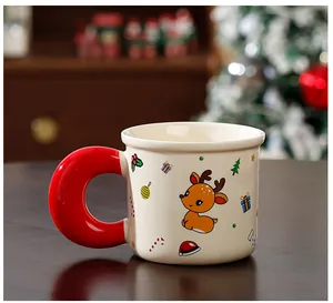 Gros plan d'un mug de Noël en céramique avec un renne mignon et une anse rouge.