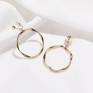 Boucles d'oreilles clips créoles dorées torsadées pour oreilles non percées sur fond soie.