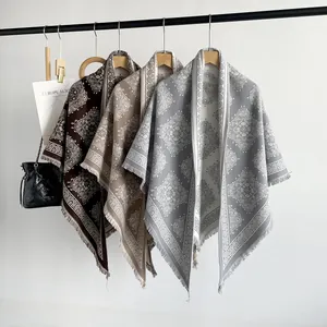 Macro view of three elegant paisley pattern triangle shawls with fringe hanging on a rack