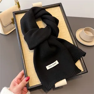 Detailansicht eines schwarzen Strickschals aus Wollmischung auf einem Dekotablett