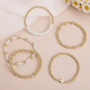 Détail d'un lot de 5 bracelets élastiques dorés avec perles et charm croix.