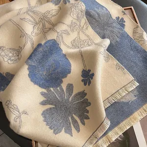 Close-up of beige and blue floral cashmere-like shawl featuring soft fringe details