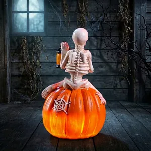 Statuetta di scheletro di Halloween su una lanterna a zucca LED arancione accesa