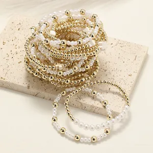 Vue détaillée des bracelets élastiques avec perles dorées, perles et breloques croix