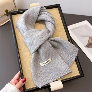 Nahaufnahme eines weichen, grau gestrickten Wollmischschals, elegant auf einem Tablett.