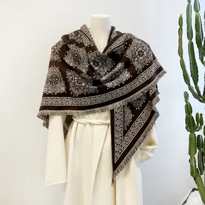 Close-up of brown paisley cashmere-like shawl draped elegantly over a white coat.