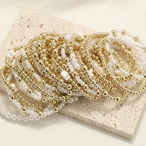 Vue détaillée de bracelets superposés en perles dorées et blanches sur pierre