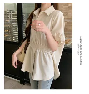Detail view of a stylish beige short-sleeve shirt with a cinched waist worn by a model