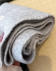 Nahaufnahme eines grauen Strickschals mit dicker Textur und hochwertigem Wollmaterial.