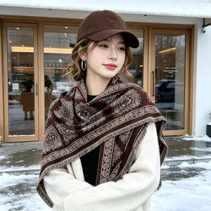 Detail view of brown paisley patterned cashmere-feel shawl on a model in snow