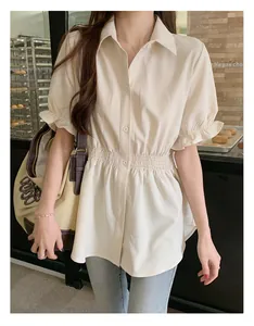 Close-up detail of a beige short-sleeve shirt featuring an elastic waist and ruffled cuffs.