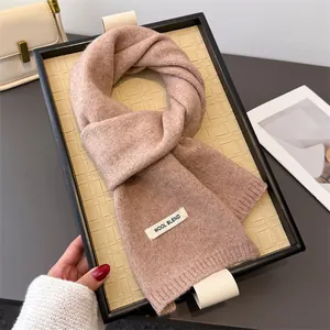 Detailansicht eines weichen Strickschals aus Wollmischung mit gewebtem Textiletikett.