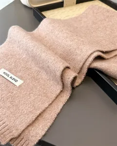 Detailansicht eines weichen Strickschals aus Wollmischung mit Textur und Materialetikett.