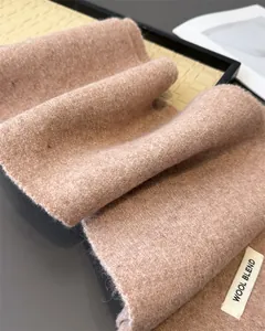 Nahaufnahme eines weichen rosa Strickschals aus Wollmischung mit Fokus auf Materialetikett