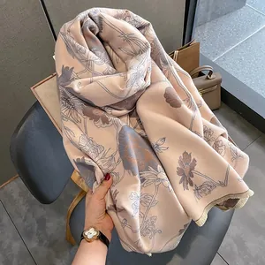 Detailed view of beige faux cashmere shawl with blue floral watercolor print and fringe.