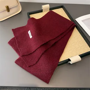 Nahaufnahme eines weinroten Wollmischschals mit Stofftextur und Etikettendetail
