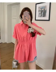 Pink short-sleeved waisted shirt worn by a model in a casual indoor setting