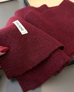 Detailansicht der weichen bordeauxroten Strickschal-Struktur mit Wollmischungsetikett