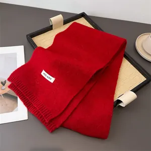 Detailansicht eines roten Strickschals aus Wollmischung mit Textur und Stoffetikett