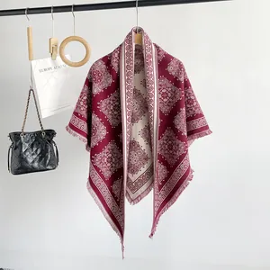 Detailed view of burgundy faux cashmere shawl with paisley pattern and fringe.