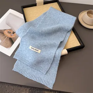 Nahaufnahme des weichen hellblauen gestrickten Wollmischschals mit Textiletikett