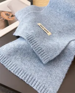 Detailaufnahme eines hochwertigen blauen Strickschals mit dekorativem Wollmischung-Etikett