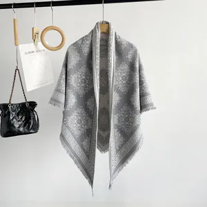 Detailed view of grey cashmere-like shawl with intricate paisley patterns and fringe edges