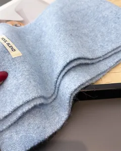 Nahaufnahme des hellblauen Wollmischschals mit weicher Strickstruktur und Etikett