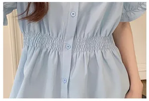 Detailed macro view of light blue summer shirt showing elastic smocked waist and button design
