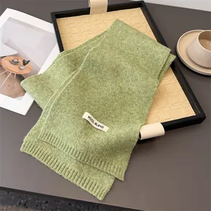 Detaillierte Nahaufnahme eines grünen Strickschals aus Wollmischung mit feiner Textur