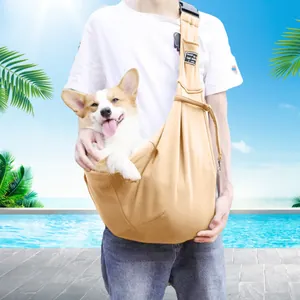 Adjustable khaki pet sling carrier bag shown in use with a small dog in an outdoor setting
