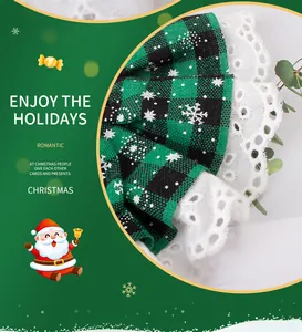 Detailopname van groen geruite kerstslabbetje voor huisdieren met wit kant en sneeuwvlokkenpatroon.