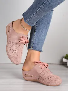 Vue détaillée des mules compensées rose poudré avec motifs floraux découpés au laser