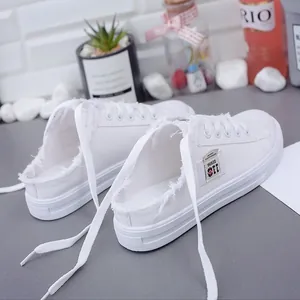 Zapatillas de lona blancas sin espalda con detalles de flecos y diseño sin cordones